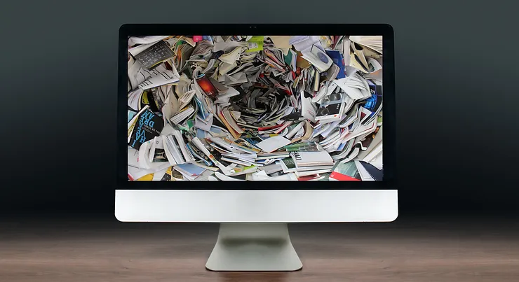 a computer displaying a clutter of paper